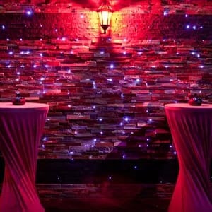 LE WE CLUB cover photo showing a chic lounge setting with red and purple uplighting, glossy wall decor, and draped tables in Paris.