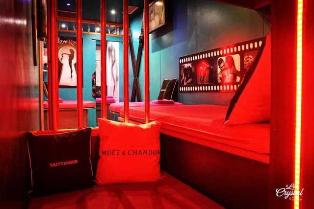 Salon rouge avec accents LED allumés, banquette capitonnée avec sacs Moët & Chandon et panneaux à thème cinéma sur le mur au Crystal.