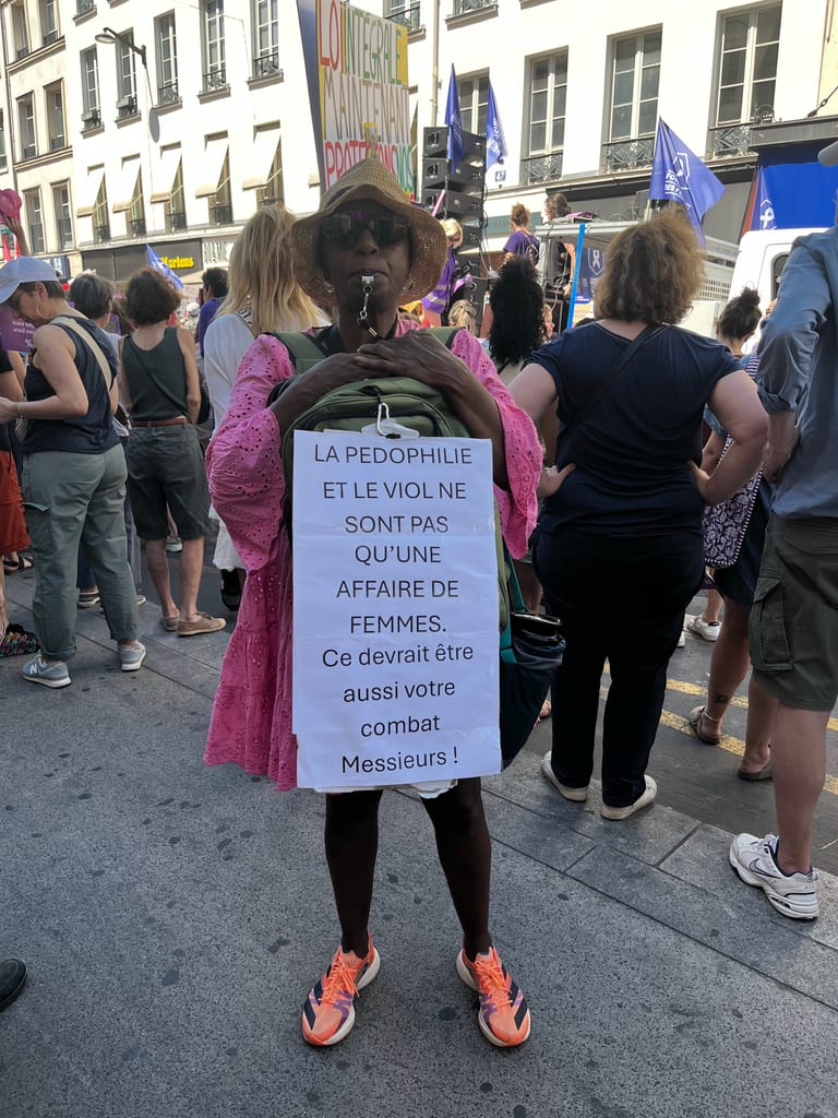 A person holds a poster saying that pedophilia and violence are not just a women's issue during a march.