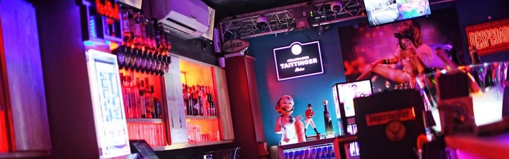 Couverture de @Le Crystal Club Libertin - Cap d'Agde montrant un bar de nuit éclairé au néon, avec des lumières colorées, des étagères de bouteilles et la signalétique du club.