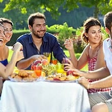 Photo of @AMITIÉ LOISIRS ENTRE NOUS showing a sunny outdoor picnic, with friends clapping around a table in a green park.