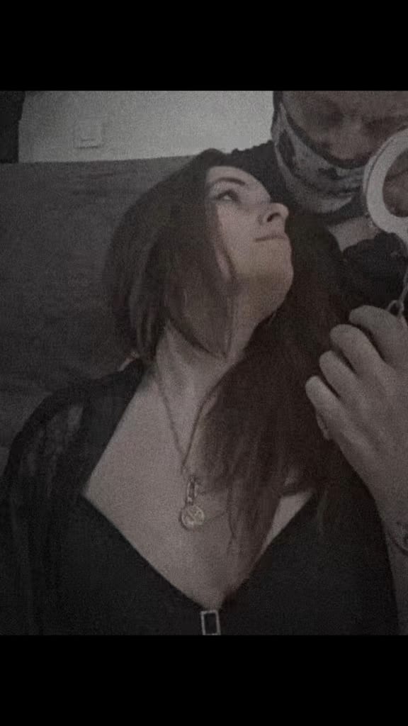 A candid, dimly lit moment on a sofa, with the couple behind Eden Coquin sitting close together in dark clothing.